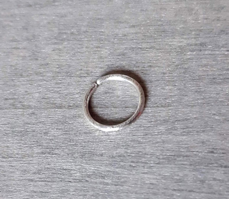 Brilliant hoop earring in sterling silver against a wooden background.