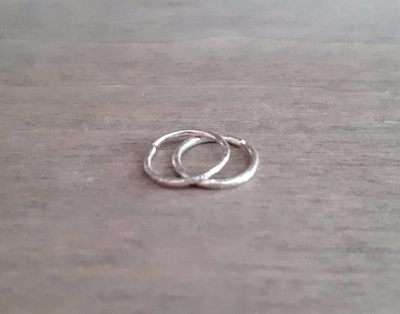 Brilliant hoop earrings in sterling silver against a wooden background.