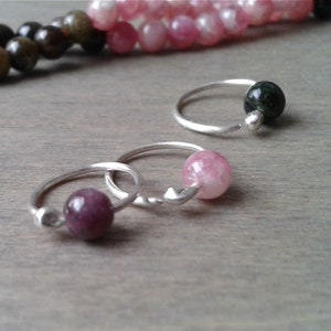 Tourmaline hoops against a wooden background.