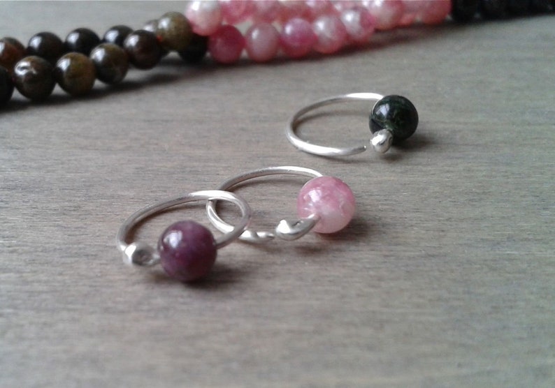 Tourmaline hoops against a wooden background.