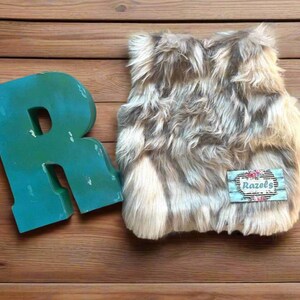 Cozy and stylish Kids' Fur Vest in a blend of grey, black, brown, and cream. Perfect for layering over any outfit, this well-made vest keeps your child warm and photo-ready. The versatile colors make it easy to mix and match with her wardrobe.