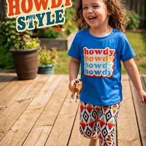 Child wearing a blue shirt with 'howdy' text, standing on a wooden deck with 'Retro Howdy Style' text above.