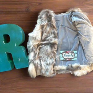 Cozy and stylish Kids' Fur Vest in a blend of grey, black, brown, and cream. Perfect for layering over any outfit, this well-made vest keeps your child warm and photo-ready. The versatile colors make it easy to mix and match with her wardrobe.