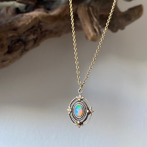 Peut inclure: Un collier en chaîne dorée avec un pendentif en forme d'ovale en opale serti dans un cadre en laiton avec un motif décoratif.