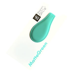 Puede incluir: Un clip de aceite magnético azul turquesa con el texto "Magnetic OliClip" y "oli block" en negro. El texto "MatteGreen" está impreso en azul turquesa sobre un fondo blanco.