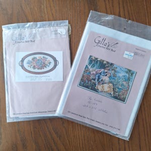 以下が含まれることがあります： 2つのGitta's Charted Petit Pointキット。1つは楕円形のフレームに花の模様があり、もう1つは庭のシーンのカップルを描いています。どちらのキットもプラスチックパッケージに入っており、「Gitta's Charted Petit Point」のテキストが含まれています。
