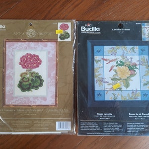 May include: Two Bucilla counted cross stitch kits. The first kit is for a geranium flower and is titled "Anna Griffin's Geranium". The second kit is for a camellia tea rose and is titled "Camellia Tea Rose".