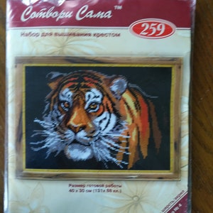 May include: A cross-stitch kit featuring a close-up of a tiger's face. The kit includes a pre-printed canvas, embroidery floss, and instructions. The finished project will measure 40 x 30 cm.