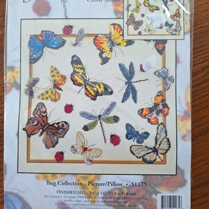 Könnte beinhalten: Ein Zählkreuzstich-Muster mit einer Sammlung von bunten Schmetterlingen und Libellen auf weißem Hintergrund. Das Muster trägt den Titel "Bug Collection - Picture/Pillow" und hat eine fertige Größe von 14 Zoll mal 14 Zoll.