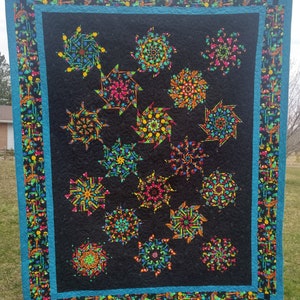 Puede incluir: Un edredón grande y colorido con un fondo negro y vibrantes patrones de estrellas. El edredón presenta un borde turquesa y un borde estampado con motivos tropicales. Las estrellas están llenas de colores brillantes.