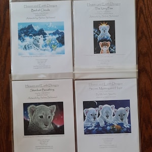 Puede incluir: Cuatro portadas de papel cartulina blanco con imágenes coloridas de cachorros de león blanco sobre una tierra azul y verde. Los títulos son "Cama de nubes", "Los muy pocos", "Respiración de polvo de estrellas" y "Secreto, misterio y esperanza".