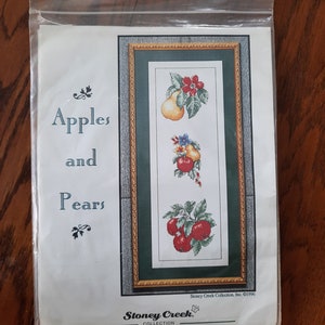 Pode incluir: Um padrão de ponto cruz com um desenho emoldurado de maçãs e peras com flores. O padrão é intitulado "Apples and Pears" e é da coleção Stoney Creek, Inc. ©1996.