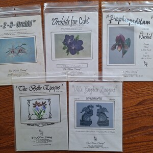 May include: Five different cross-stitch patterns featuring floral and dragon designs. The patterns are titled "1-2-3-Orchid", "Orchids for Cole", "Paphiopedilum Orchid", "The Belle Epoque", and "Ville Borghese Dragons".