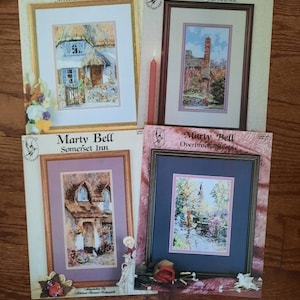 Puede incluir: Cuatro patrones de punto de cruz con acuarelas de encantadoras casas de campo. Los patrones se titulan "Sweetheart Thatch", "Horsham Farmhouse", "Somerset Inn" y "Overbrook Steeple".