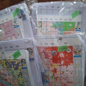 May include: Three cross-stitch kits with colorful patterns and numbers. The kits are labeled "Athens", "Madrid", and "Poa".