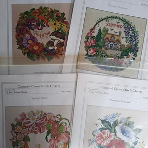 以下が含まれることがあります： 花輪と花束をモチーフにした、カウントクロスステッチのチャートが4つあります。チャートのタイトルは、「秋のリース」、「夏の別荘」、「ピンクの春」、「夏のブーケ」です。