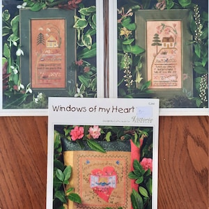 May include: Three cross stitch patterns featuring floral borders and a house with a heart-shaped window. The patterns are titled "Snowdrop Hill Sampler", "Honeysuckle Hill Sampler", and "Windows of My Heart".