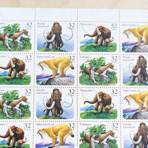 May include: A sheet of 12 US postage stamps featuring extinct animals. The stamps depict a woolly mammoth, saber-tooth cat, and mastodon. Each stamp has a value of 32 cents.