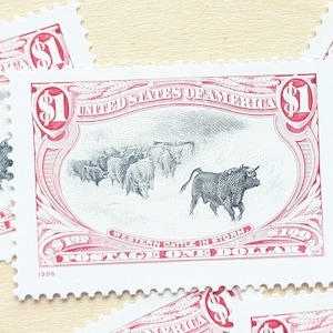 May include: A collection of vintage postage stamps featuring a detailed illustration of cattle in a storm. The stamps are red and white, with the text "UNITED STATES OF AMERICA" and "WESTERN CATTLE IN STORM". Each stamp is worth one dollar.