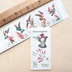 May include: Five different hummingbird stamps with colorful flowers. The stamps are part of a set of twenty stamps and cost $5.80. The text on the stamps reads "USA 29c".