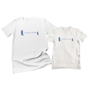 May include: Two white t-shirts with blue penguin illustrations and the text "Like Dad Like Son".