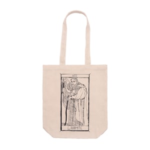 Op de afbeelding: Beige draagtas met een zwart-wit illustratie van een tarotkaart, De Kluizenaar. De kaart toont een figuur in een gewaad met een lantaarn en een staf. De woorden "VIII" en "L'HERMITE" staan op de tas.