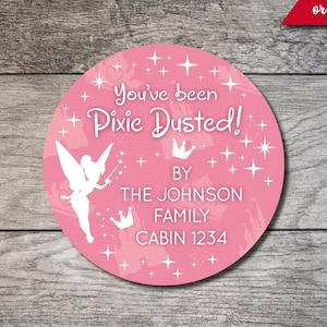 May include: Pink round sticker with a white fairy silhouette, stars, and the text "You've been Pixie Dusted!" with the words "BY THE JOHNSON FAMILY CABIN 1234" below.