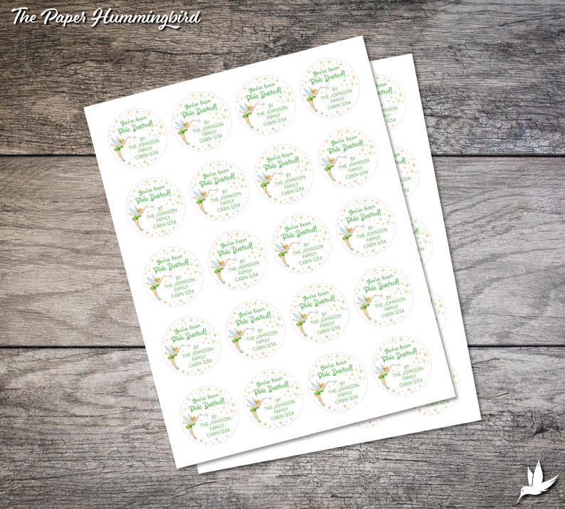 May include: A sheet of white sticker paper with 24 round stickers featuring a green fairy with a yellow dress and gold glitter. The stickers say "You've been dusted! By The Johnson Family Cabin 1234".