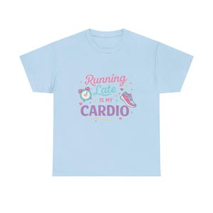 May include: Light blue t-shirt with the phrase "Running Late is my Cardio" in pink, purple, and green. The design includes a clock, a running shoe, and hearts. A casual, comfortable tee for fitness enthusiasts.