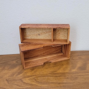 May include: Two rectangular wooden boxes with a natural brown finish. The top box features a single internal divider, while the bottom box has an open interior with a semi-circular cutout on the front edge for easy access to the contents inside.