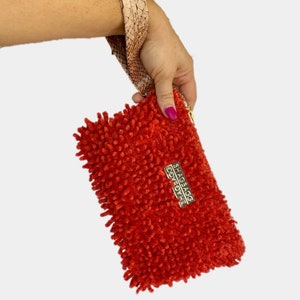 May include: A bright red fuzzy clutch purse with a gold zipper and a gold metal tag that says "SHAGBAG" in all caps.