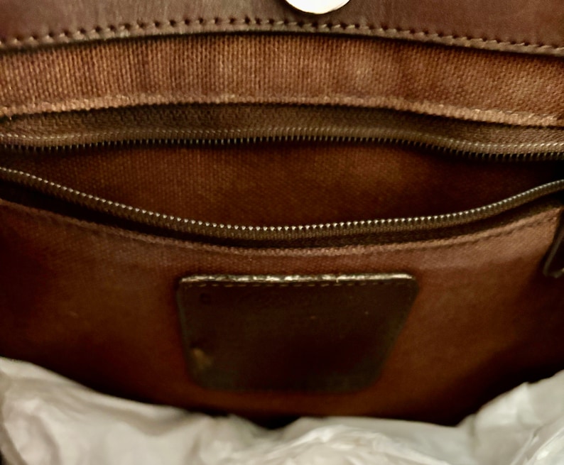 Puede incluir: El interior de un bolso de cuero marr&oacute;n con un bolsillo con cremallera y un parche de cuero marr&oacute;n.