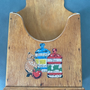 May include: Wooden wall mounted spice rack with a painted design of three jars labeled "Mustard", "Bay", and "Curry".