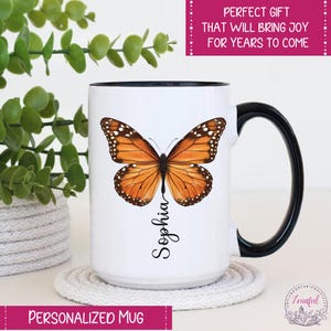 Peut inclure: Une tasse en c&eacute;ramique blanche avec une anse noire. La tasse pr&eacute;sente un papillon color&eacute; aux ailes orange, jaunes et noires. Le nom "Sophia" est &eacute;crit verticalement sous le papillon.