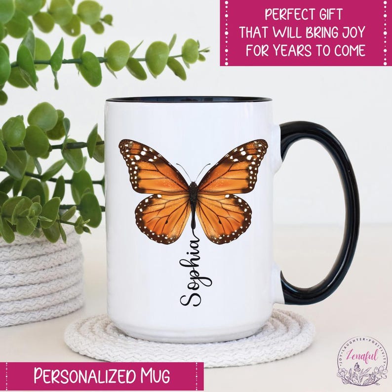 Peut inclure: Une tasse en c&eacute;ramique blanche avec une anse noire. La tasse pr&eacute;sente un papillon color&eacute; aux ailes orange, jaunes et noires. Le nom "Sophia" est &eacute;crit verticalement sous le papillon.