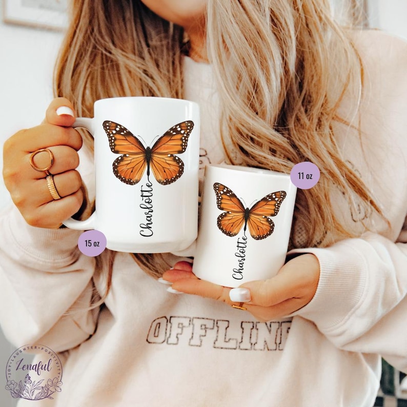 Peut inclure: Deux tasses en c&eacute;ramique blanche avec un motif de papillon et le nom "Charlotte" imprim&eacute; dessus. La tasse de gauche est de 15 oz et la tasse de droite est de 11 oz.