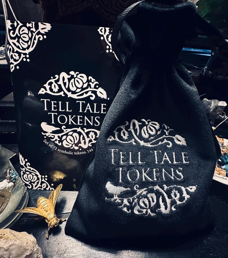 May include: A black velvet bag with white embroidery that reads "Tell Tale Tokens" and "Set of 72 symbolic tokens. 144."