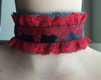 May include: A red and black lace choker with a glittery red ribbon. The choker is made of a soft, stretchy fabric and has a delicate lace trim.
