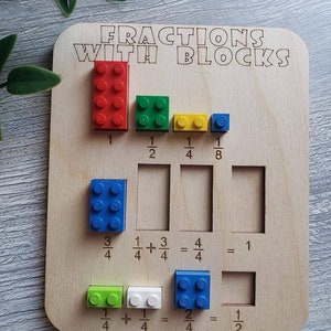 May include: A wooden board with the words "FRACTIONS WITH BLOCKS" printed on it. The board has slots for different colored Lego blocks to represent fractions. The fractions are 1, 1/2, 1/4, 1/8, 3/4, 1/4 + 3/4 = 4/4 = 1, 1/4 + 1/4 = 2/4 = 1/2.