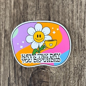 May include: A vibrant sticker with a smiling daisy holding a yellow teacup. The background features a retro wavy design in pink, orange, purple, and blue. Text reads "Have the day you defunded."