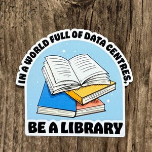 Peut inclure: Un autocollant découpé représentant une pile de livres avec un livre ouvert au sommet. Le fond est bleu clair avec de petites étoiles blanches. Le texte indique : IN A WORLD FULL OF DATA CENTRES, BE A LIBRARY. Les livres sont bleus, jaunes et rouges.