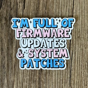 Peut inclure: Un autocollant avec le texte "I'm full of firmware updates & system patches" en lettres bleues, roses et blanches avec des contours noirs.