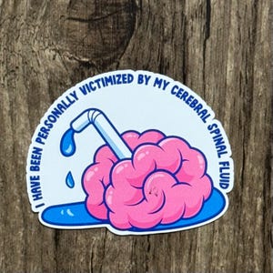 May include: A sticker with a cartoon brain design. The brain is pink with a white and blue straw inserted. The text around the brain reads "I HAVE BEEN PERSONALLY VICTIMIZED BY MY CEREBRAL SPINAL FLUID."