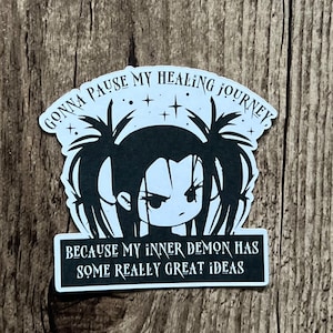 May include: Black and white sticker featuring a cartoon girl with pigtails and the text "GONNA PAUSE MY HEALING JOURNEY, BECAUSE MY INNER DEMON HAS SOME REALLY GREAT IDEAS."