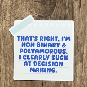 May include: A white sticker with blue text that reads: "THAT'S RIGHT, I'M NON BINARY & POLYAMOROUS. I CLEARLY SUCK AT DECISION MAKING." The sticker has a light blue tab at the top.