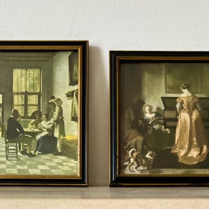 Könnte beinhalten: Zwei gerahmte Kunstdrucke mit schwarzen und goldenen Rahmen. Einer zeigt eine Gruppe von Menschen an einem Tisch, der andere eine Frau in einem goldenen Kleid in der Nähe eines Musikinstruments. Beide sind klassische Gemälde.