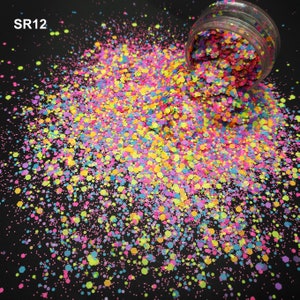Pode incluir: Uma vibrante variedade de glitter colorido, incluindo rosa, amarelo, azul e verde, derrama-se de um recipiente transparente. O glitter tem várias formas e tamanhos, criando um efeito deslumbrante. O texto "SR12" é visível.