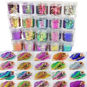 Può includere: Una collezione di piccoli vasetti trasparenti pieni di glitter colorati in varie tonalità, tra cui oro, rosa, viola e verde. Sotto i vasetti ci sono diverse mani coperte di glitter, che mostrano le diverse combinazioni di colori.