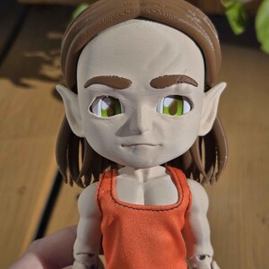 May include: A 3D printed figurine of a person with brown hair, green eyes, and a muscular build. The figurine is wearing an orange tank top and blue jeans.