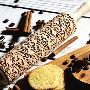 May include: A wooden rolling pin with a carved design of cartoon tigers. The rolling pin is on a white wooden surface with coffee beans, cinnamon sticks, and star anise.